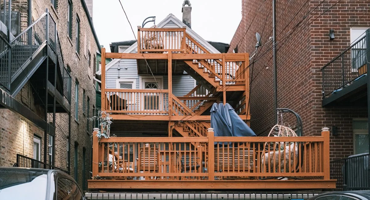 Multi-level wooden deck between urban buildings, showcasing unique architectural design.
