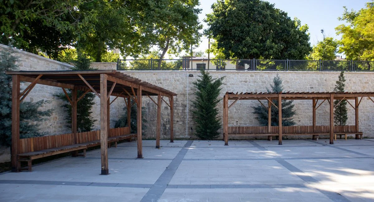 Peaceful outdoor courtyard with wooden pergolas and lush greenery in Elazığ, Türkiye.